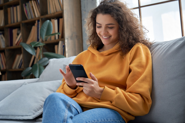 Girl smiling at her phone on the sofa