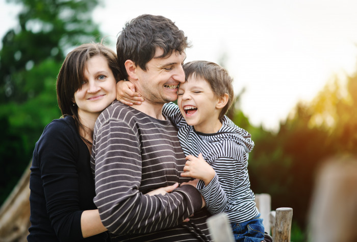 Family hugging and smiling outdoors