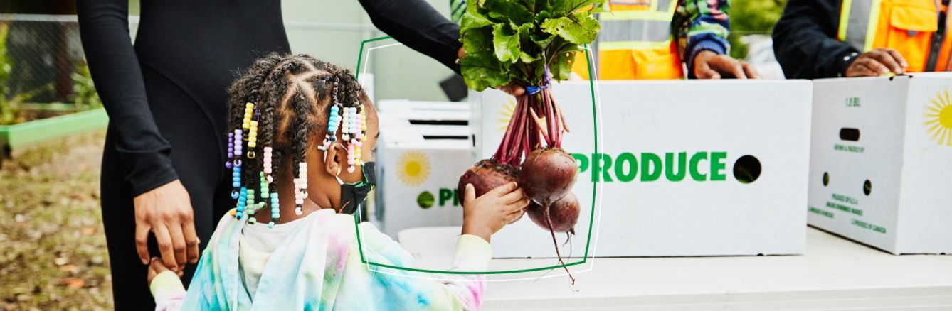 Young child collecting onions from a produce stall