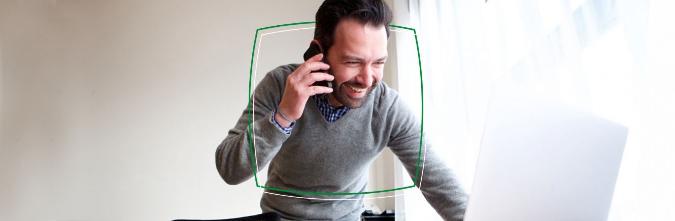 Smiling man on phone and laptop at home