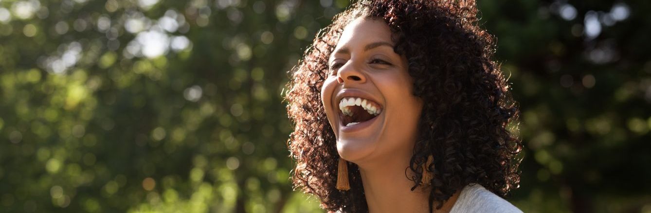 Woman laughing near some trees