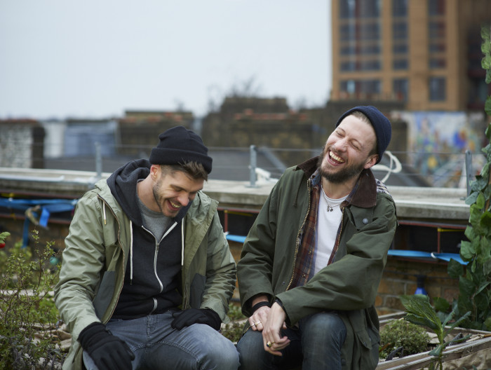 Two men smiling and chatting outdoors