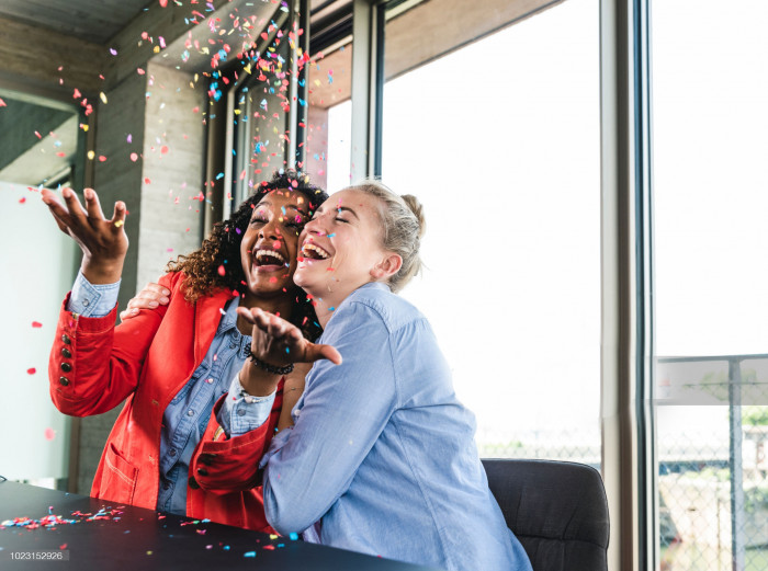 Female colleagues throwing confetti and smiling